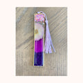 Example of a sold custom gold bezel bookmark with purple resin, glitter, flower, and tassel